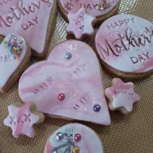 Picture Shows a selection of Biscuits with pink fondat icing and happy mother day embossed in the biscuits.