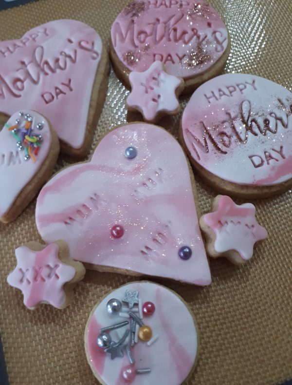 Picture Shows a selection of Biscuits with pink fondat icing and happy mother day embossed in the biscuits.